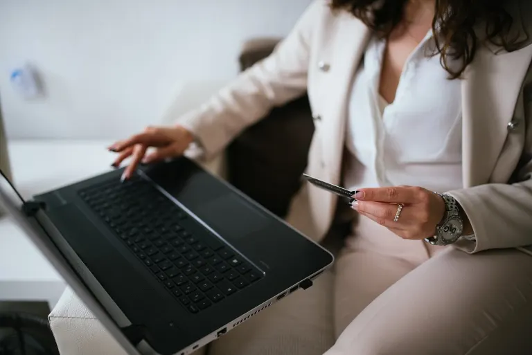 Business professional engages in online shopping from home workspace while using credit card