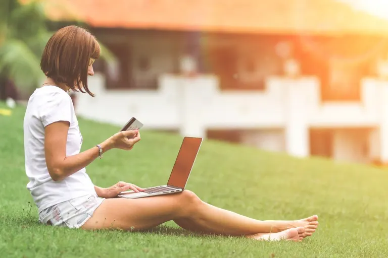 Woman online shopping concept. Woman in the green park with modern laptop. Bali island.