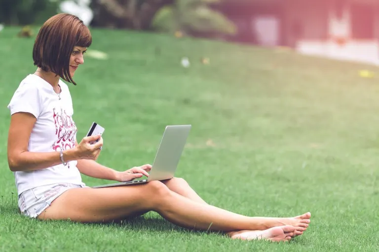 Woman online shopping concept. Woman in the green park with modern laptop. Bali island.